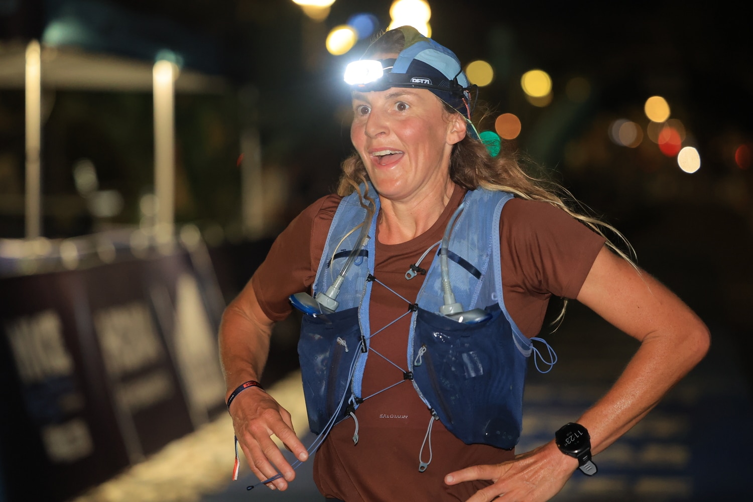 A woman arrives in the night with her flashlight on her head visibly tired but happy to have finished.
