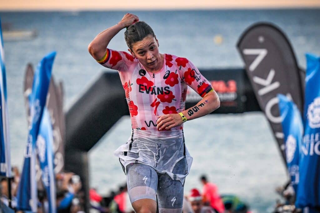 an athlete comes out of the water in a wetsuit with red flowers.