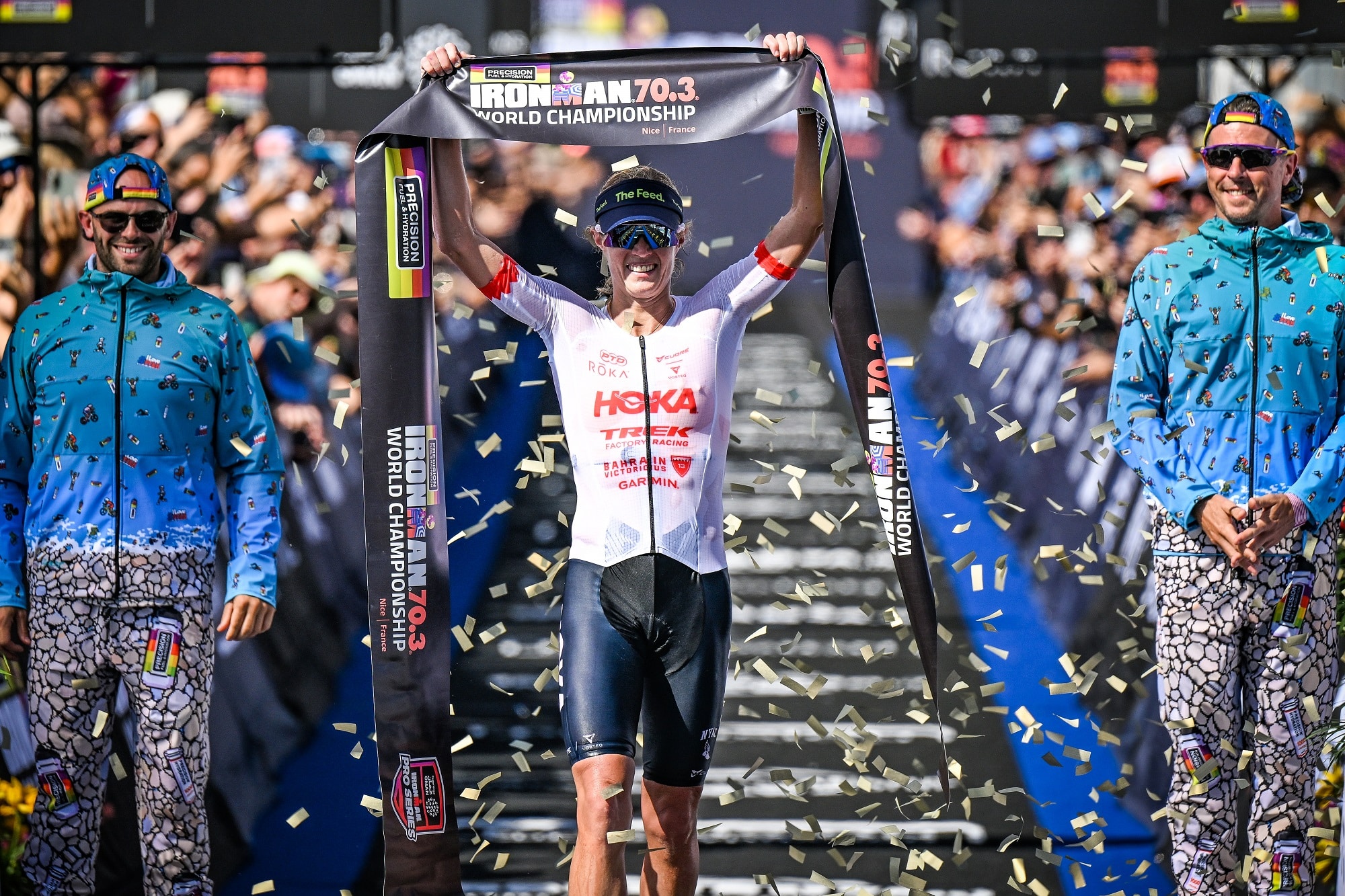 The winner of the 2026 edition of the 2026 Ironman World Championship Taylor Knibb raises her arm with the banner symbolizing the finish line in her hands.