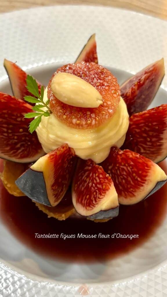 A fig tartlet with orange blossom mousse in the shape of a flower.