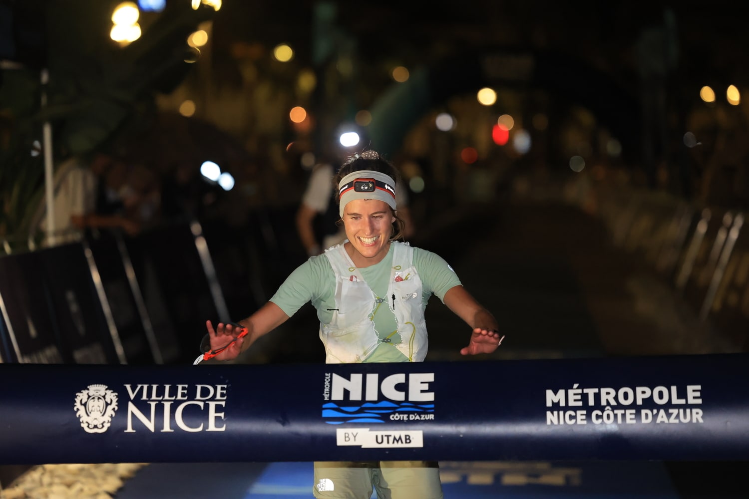A woman arrives and is about to grab the finish line banner with her hands.